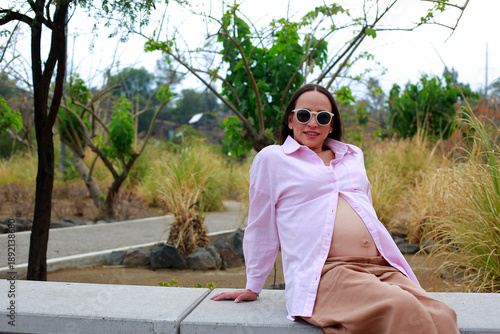 Pretty pregnant woman sitting in the park