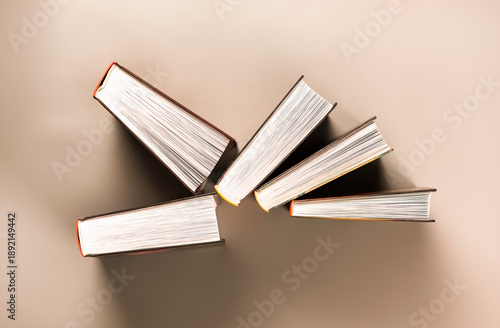 Group of books stands chaotically against red background.