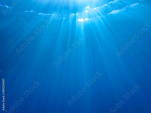 Ocean blue underwater with sunrays, Underwater Sea Deep Water Abstract Sunshine, sea wave , clean waters in summer time, Natural underwater seascape, sand on ocean floor and water surface with sunligh