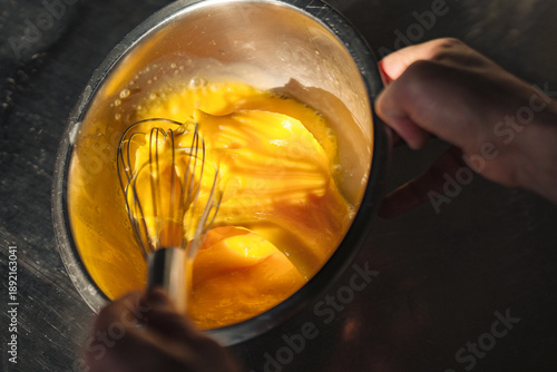 Rustic kitchen action showing eggs being stirred lovingly in copper pot