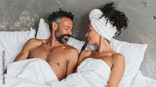 Happy couple enjoys an intimate moment in bed. They enjoy their active sexual life. Heterosexual couple after shower