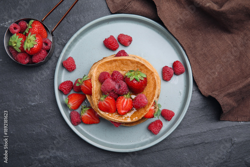 Obraz na plátně Tasty pancakes served with honey and berries on black table, flat lay