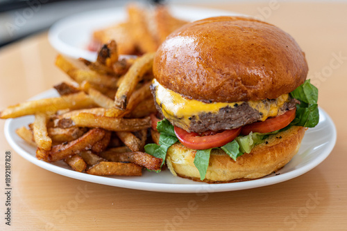Foto A cheeseburger with lettuce and tomato and fries on a white plate at a modern Am