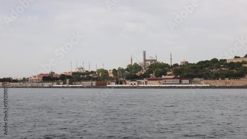 View of historic Istanbul skyline across water, featuring Hagia Sophia and Blue Mosque under cloudy sky.