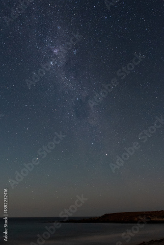 Milky way galaxy over dark ocean coast at night