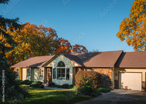 Foto View of Midwestern suburban house before sunset in autumn; large colorful trees