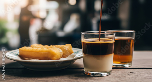Pouring espresso into layered coffee drink with fried pastry and tea