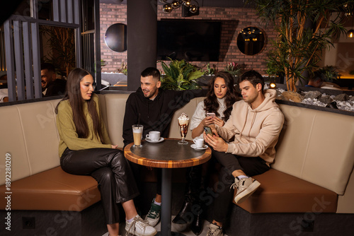 Group of friends sitting at a bar table in a café and having fun