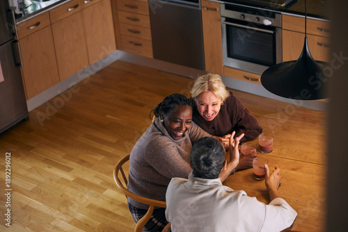High angle view of childhood friends enjoying drinks with each other while sitting at table in home