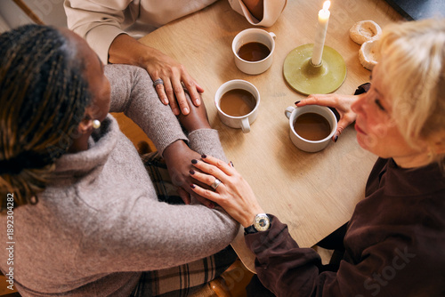 High angle view of hot chocolate cups kept on table with female friends spending leisure time in home