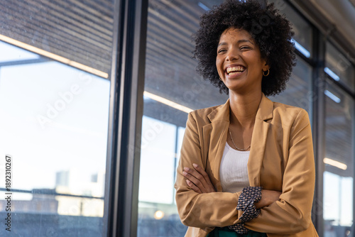 African american woman smiling by windows in office wearing blazer, copy space
