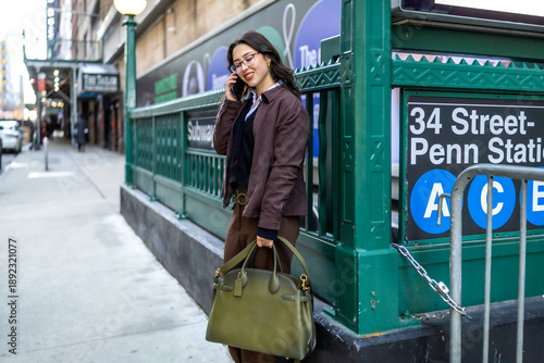 Tableau sur toile Young businesswoman talking on phone near subway station in manhattan