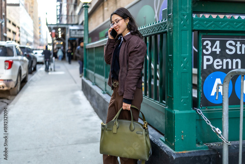 Εκτύπωση καμβά Young businesswoman talking phone, walking manhattan street holding bag