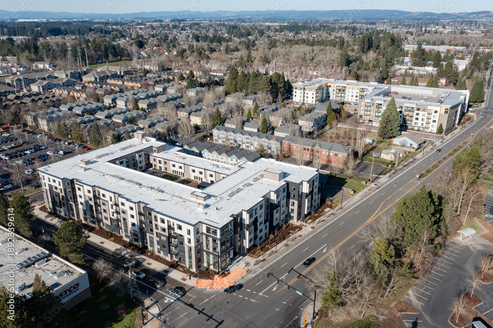 Fototapeta premium Aerial drone picture of a modern apartment complex in Beaverton, Oregon, with multi family residential buildings, surrounding neighborhood housing, streets, trees, and urban development 