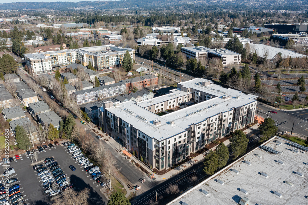 Fototapeta premium Aerial drone picture of a modern apartment complex in Beaverton, Oregon, with multi family residential buildings, surrounding neighborhood housing, streets, trees, and urban development 