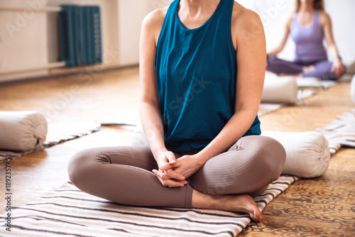 Bild auf Leinwand Female yoga practitioner in blue tank top seated in a meditative pose on a strip