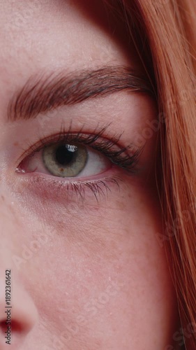 Extreme close-up macro portrait of smiling young woman freckles face. Redhead lady eyes, looking at camera. Green eyes of ginger lady. Portrait of teenager positive female opening wide her closed eyes