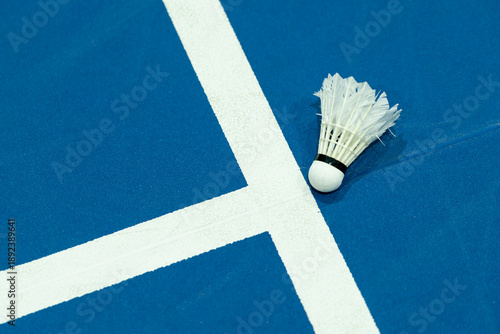 Close-up of a shuttlecock on a blue indoor sports badmonton court background.