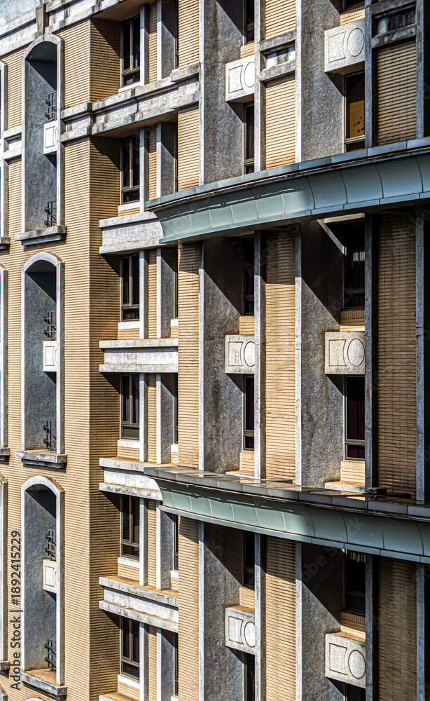 Fototapeta premium Modern building facade with rhythmic window design and dramatic sunlight and shadows 