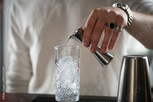 Bartender mixing gin and tonic in glass filled with ice cubes and lemon. Captures sparkle, aroma, and elegant cocktail style.
