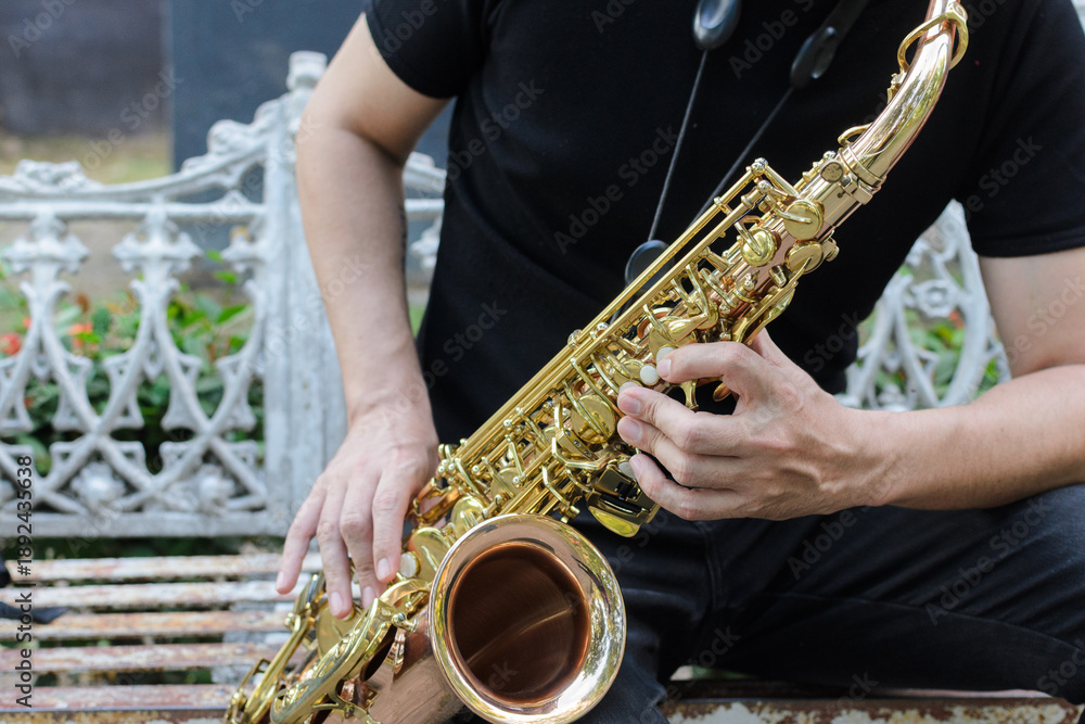 Obraz premium Authentic Musician Playing Golden Saxophone Instrument Outdoors on a Rustic Bench