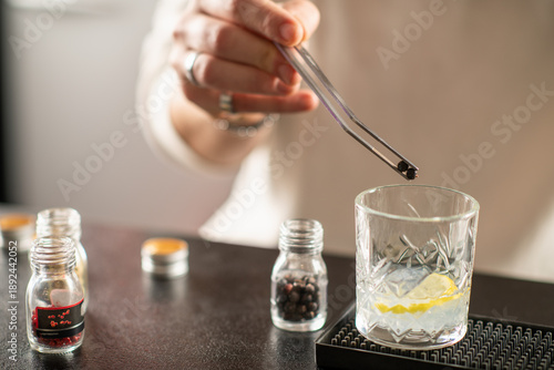 Professional barman preparing gin cocktail, adding aromatic spices into glass. Highlights fragrance, craftsmanship, and modern mixology art.