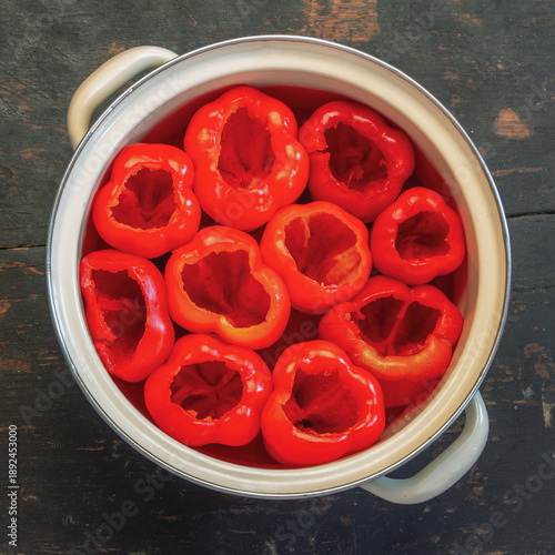 Raw, hollowed-out red bell peppers in a pot on a table, prepped and ready for stuffing top view