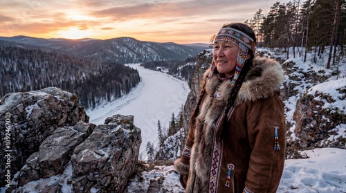 Portrait of an indigenous woman in traditional fur clothing standing on a snowy cliff at sunset. Scenic winter mountains, frozen river, cultural heritage, nature, and ethnic traditions in harmony.