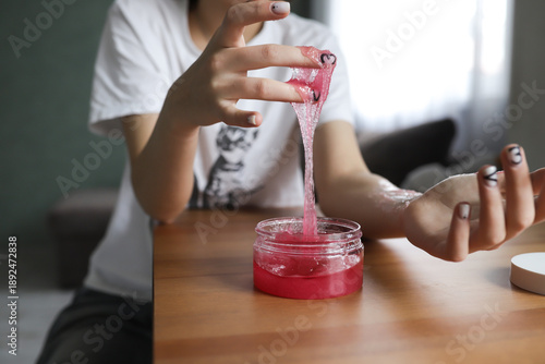 Close-up of a woman's hands in the process of skin care - a girl applies a pink scrub, gently cleansing and exfoliating the skin. The treatment symbolizes home spa care, self-care, beauty and health