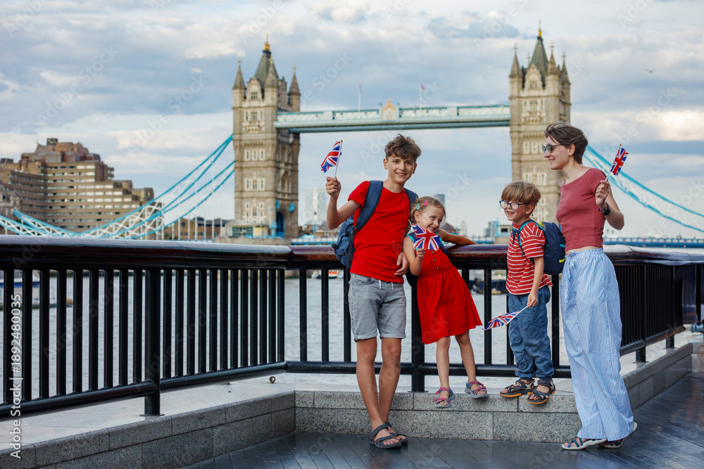 Obraz premium Tourist family with kids at the Tower Bridge hold British flags