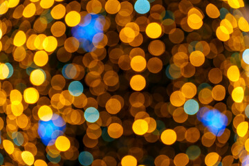 Golden and blue Christmas bokeh background with blurred festive fairy lights from a decorated holiday tree.