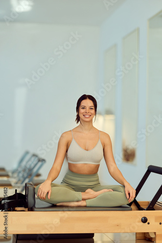 Smiling Woman Meditates in Pilates Studio on Reformer Mat For Wellness, Fitness, and Mindfulness Branding