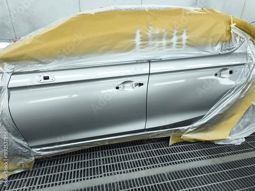 Tableau sur toile Car body repainting process with masked doors in professional spray booth, auto repair and refinishing service concept, clean workshop environment