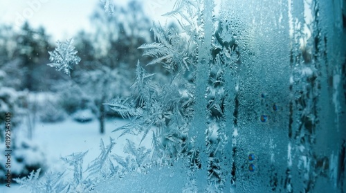 Frost patterns cover a window on a cold winter morning. Outside, snow blankets the ground and trees. The scene shows a typical chilly day in winter