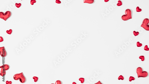 Valentine's Day background with scattered small red hearts around the edges, creating a frame. The center has a blank space for text or other content. Flat lay, top view.