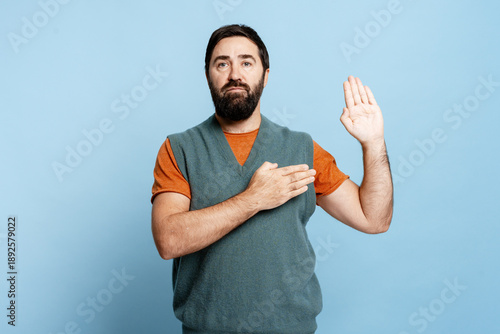 Foto Serious pensive bearded man holding hand up and on chest promise telling the tru