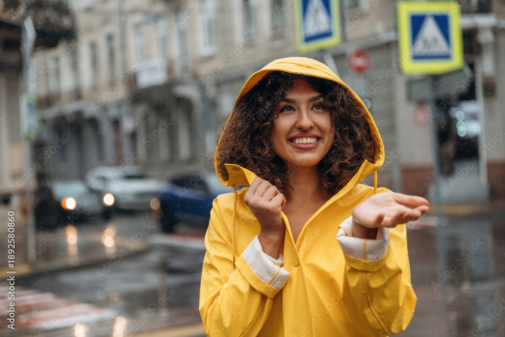 Obraz premium Against the building at background. Happy young woman in the city during the rain