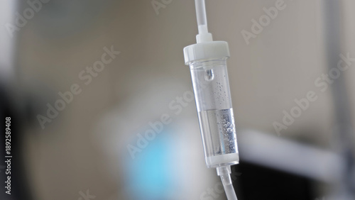 Close-up of IV drip chamber in hospital. Intravenous drip chamber filled with fluid and air bubbles, used in medical treatments for hydration, medication, and patient care.