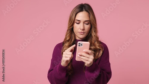 Sad upset young woman wear purple knitted sweater casual clothes hold use mobile cell phone swear read bad fake news unexpected rumor has some problem isolated on plain pastel light pink background