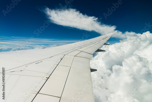 View of the plane's wing and beautiful clouds through the window during the flight.