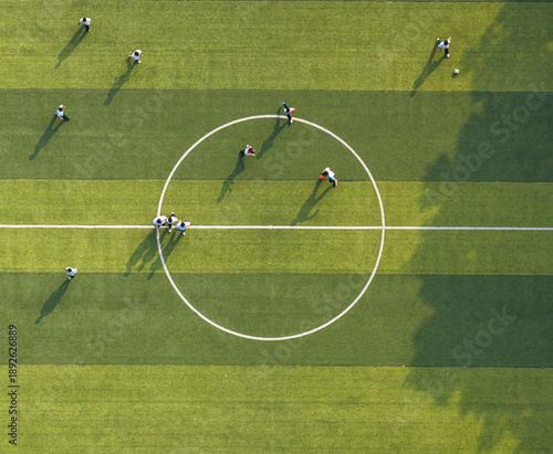 Aerial view of students playing soccer on a green campus field. Promoting physical education and teamwork during break time. Vibrant school sports scene.