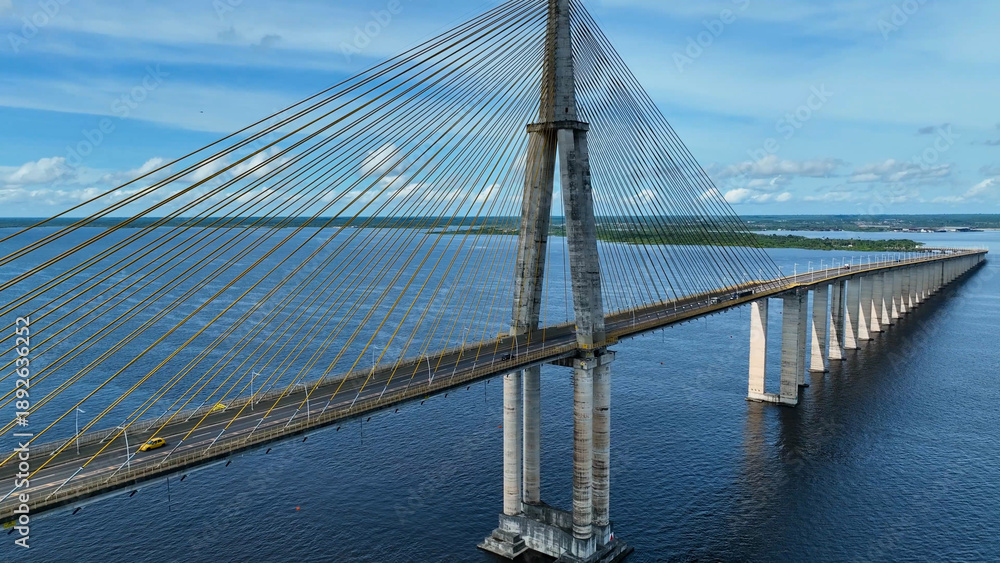 Fototapeta premium Suspension Cable Bridge In Manaus Amazonas Brazil. Birds Eye View Of Suspension Bridge With Cars Driving Across. Shore Clouds Sky Beach Sea. Shore Beach Scenic Coastline. Manaus Amazonas.