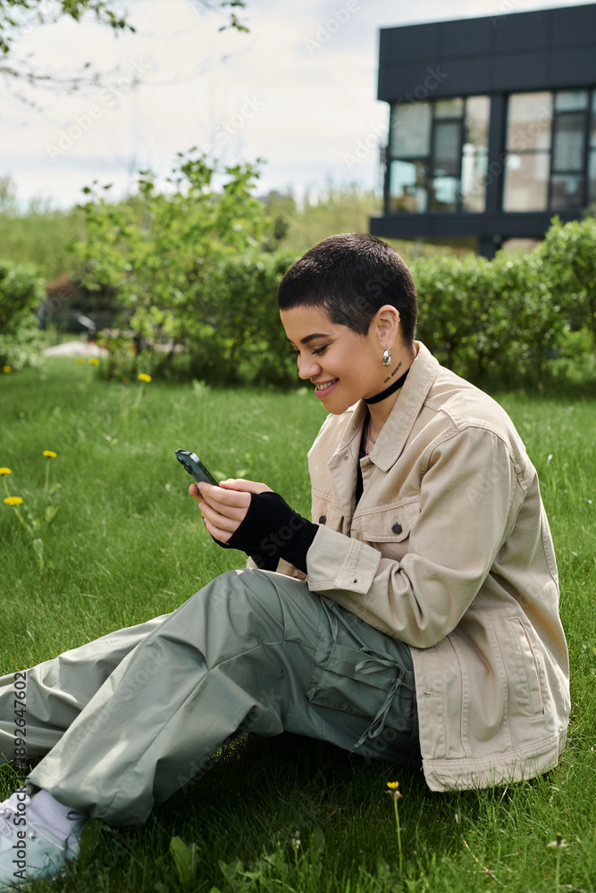 Obraz premium Young woman enjoys a sunny day outdoors in stylish jacket with smartphone