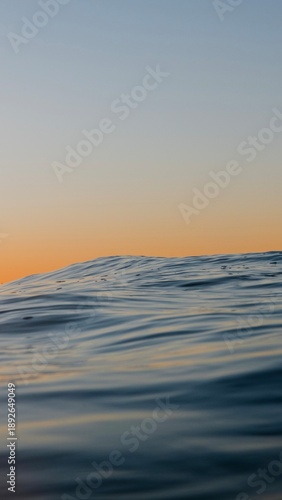 Wave during sunset in Portugal, with a golden orange sky and blue water