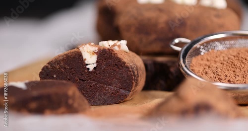 sweet brown pastry potatoes are on a serving board and paper, sweet classic cake from butter and a large amount of cocoa mixed with sponge cake and cognac, cocoa powder is scattered nearby