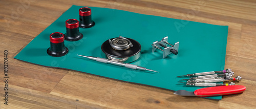 Fotografija Tools and equipment for watch repair set on a green mat indicate the work of a skilled watchmaker focusing on fine mechanics
