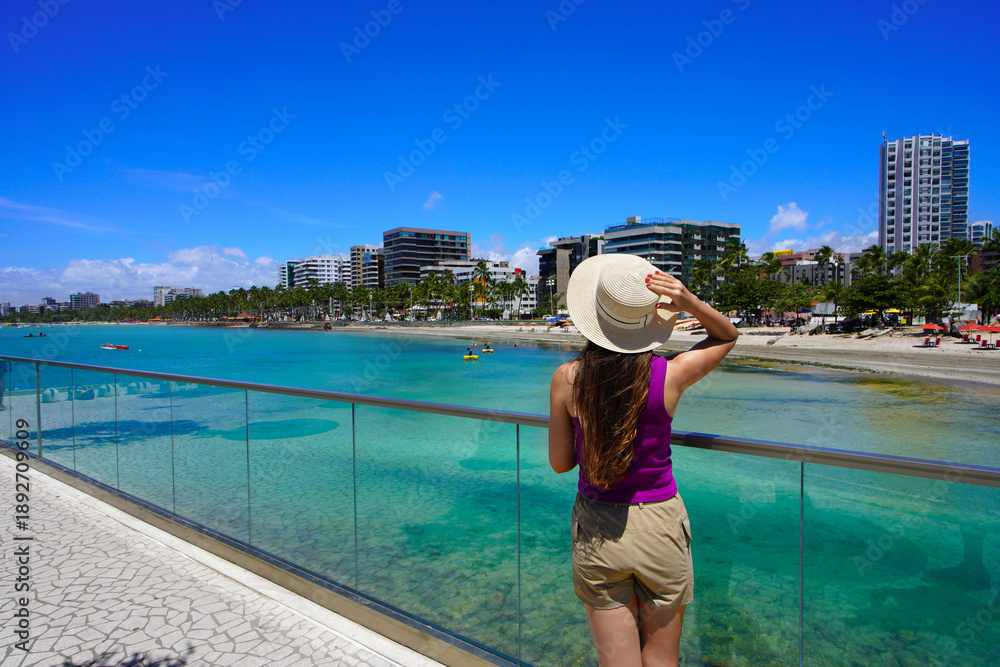 Fototapeta premium Vacation in Brazil. Rear view of young woman enjoying sight on belvedere in Maceio, Alagoas, Brazil.