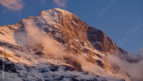 Eiger North Face in the Swiss Alps at sunset with atmospheric clouds