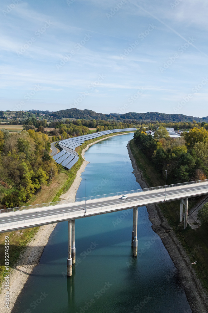Fototapeta premium Aerial view of solar panels by a river highlights clean energy and environmental responsibility.