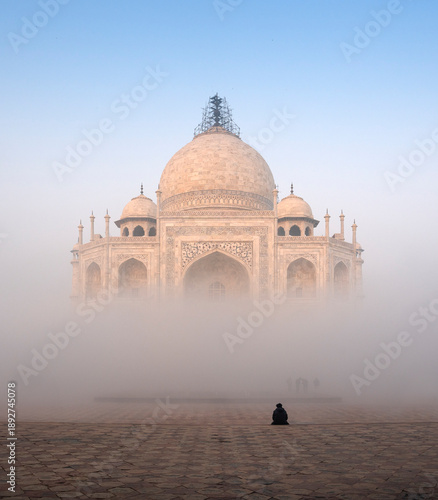 Person sitting in front of the Taj Mahal on a foggy morning